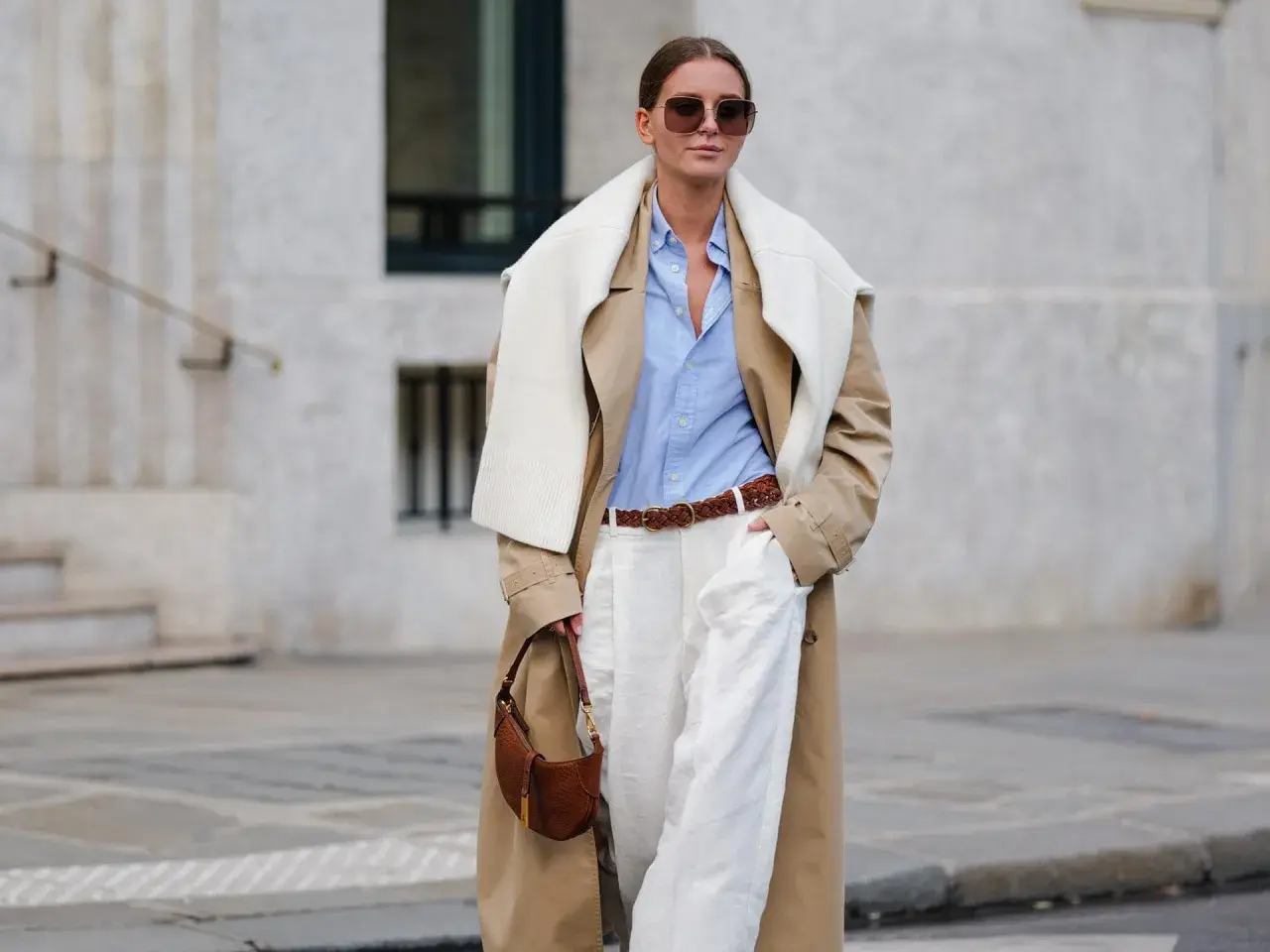 Frau im Trenchcoat, hellblauem Hemd und weißen Hosen, ein perfekter casual business look. Braune Tasche und Gürtel.