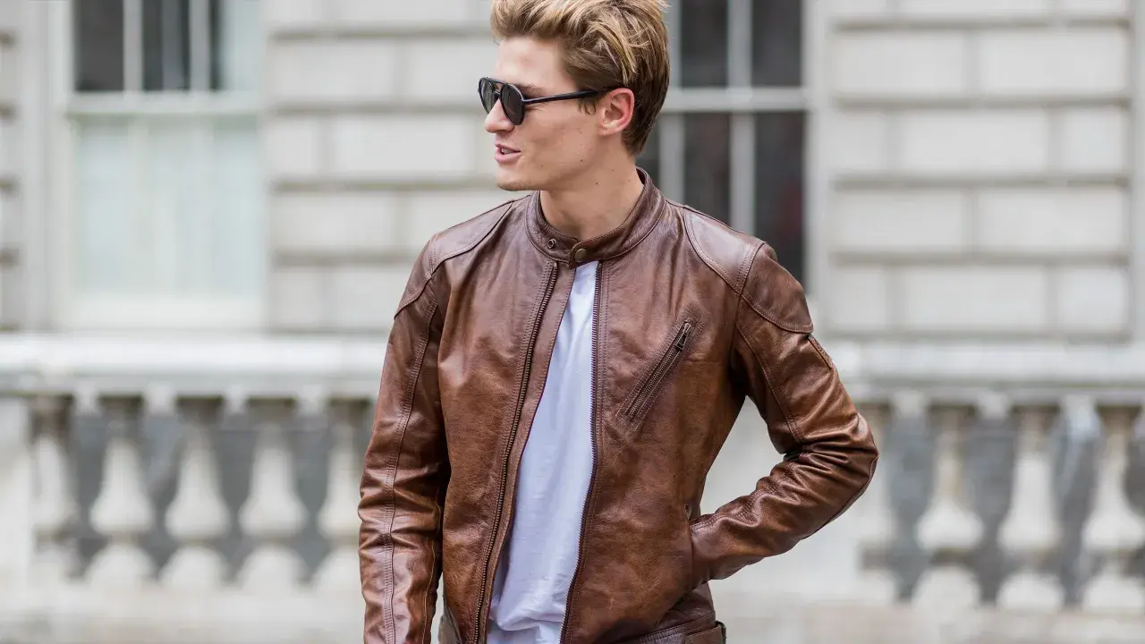 Mann mit brauner Wildlederjacke, die er reinigen möchte. Sonnenbrille und weißes T-Shirt.