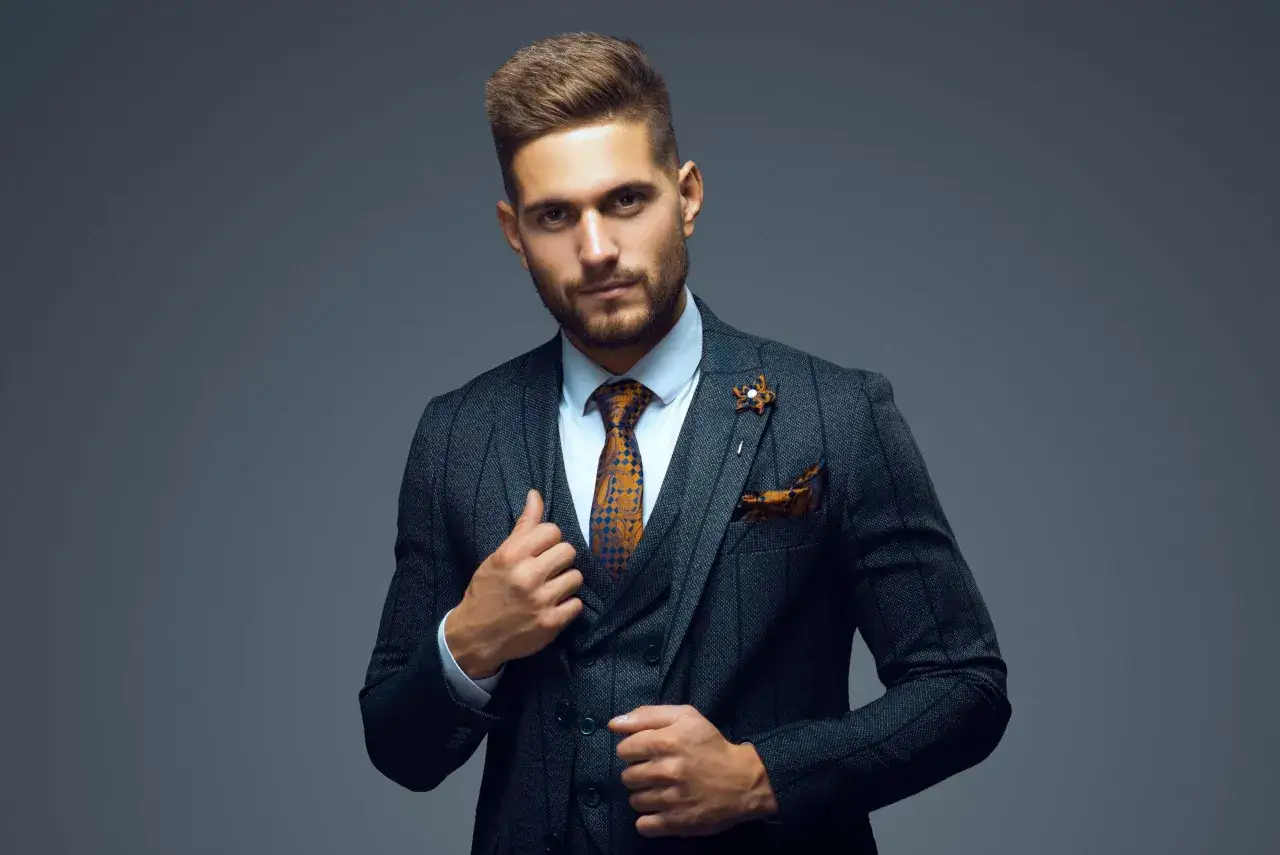 Ein Mann in stilvoller Business-Kleidung für Herren, mit grauem Anzug, gemusterter Krawatte und Einstecktuch.