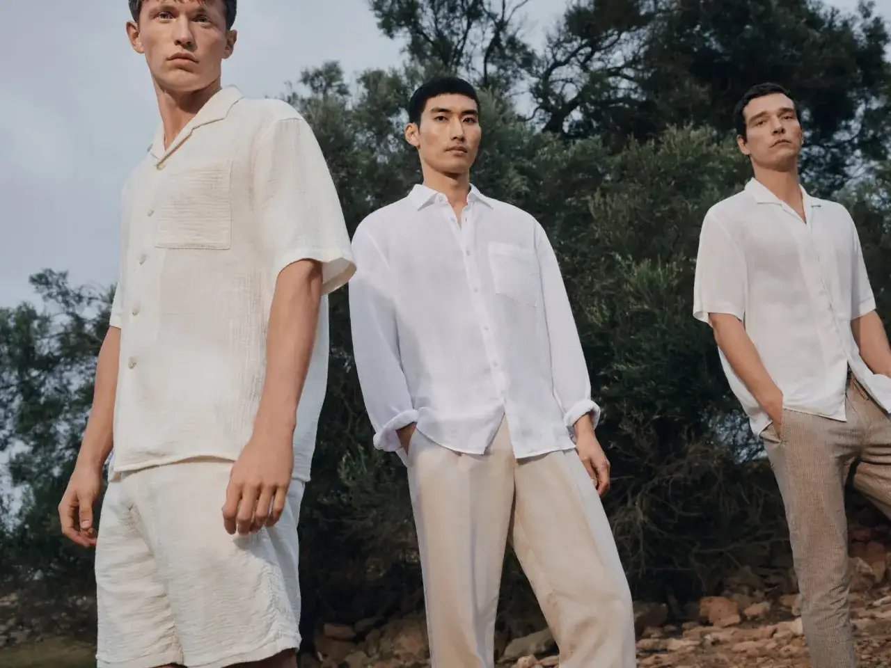 Drei Männer in leichten, hellen Outfits. Ein beige Oberteil kombinieren Herren lässig mit Shorts oder Hosen.