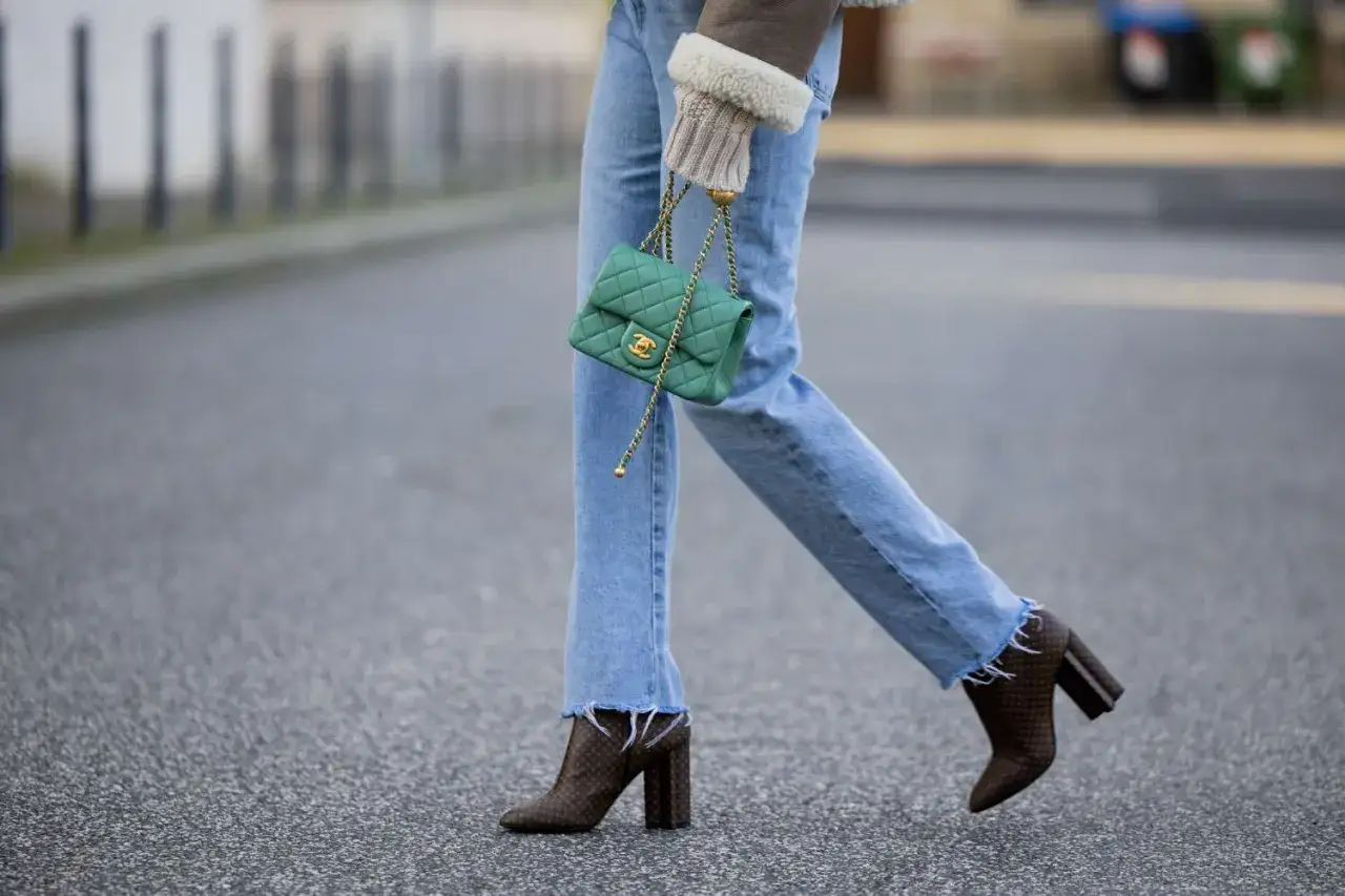 Moderne Frau kombiniert l&auml;ssige Jeans mit auff&auml;lligen Boots und einer gr&uuml;nen Chanel-Tasche.