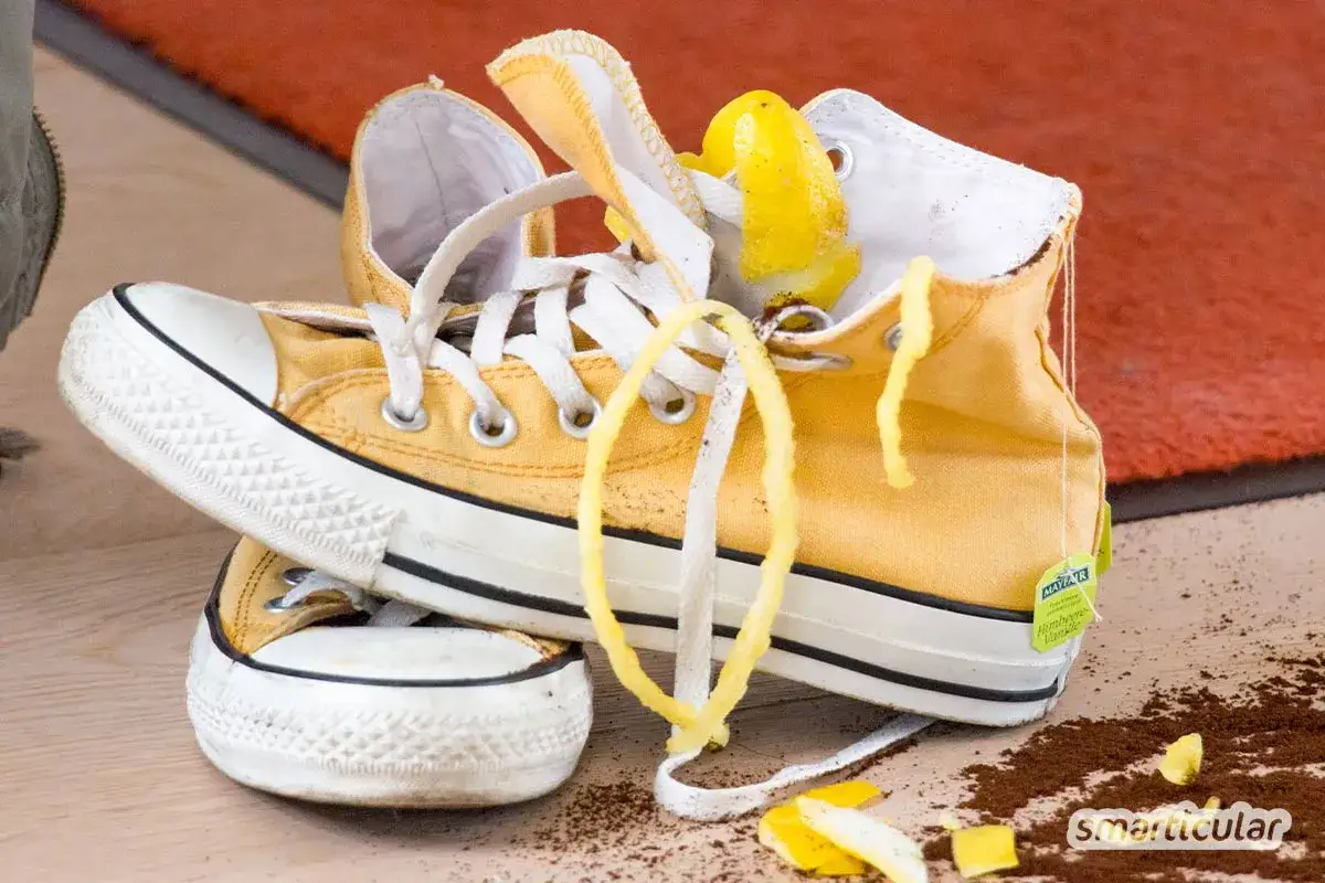 Gelbe Turnschuhe mit Zitronenschale und einem Teebeutel. Ein Hausmittel gegen Geruch: Natron in Schuhe streuen.