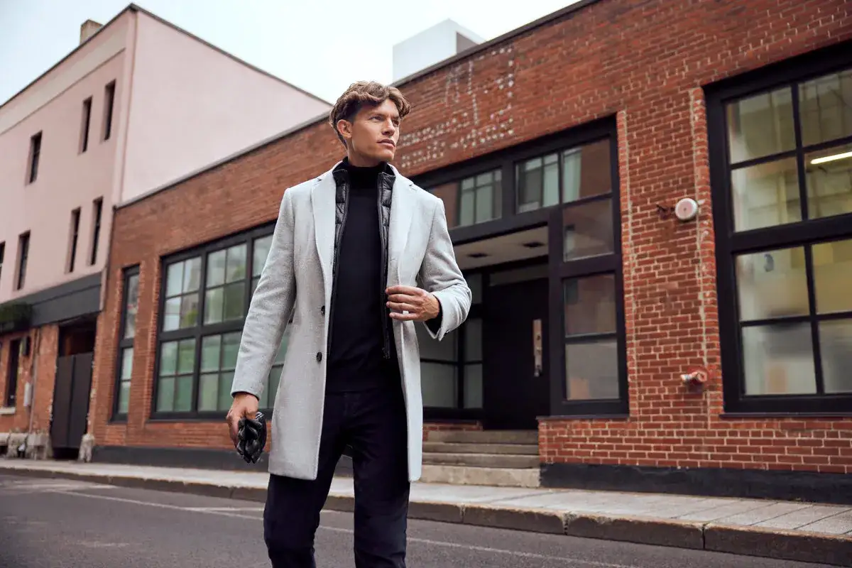 Mann im eleganten Mantel, schwarzem Rollkragenpullover und Jeans – ein perfekter dresscode chic herren für die Stadt.