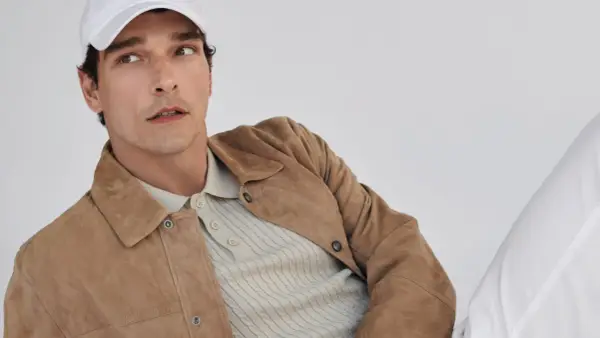 Mann mit weißer Kappe trägt einen braunen Wildleder-Anzug mit Poloshirt.
