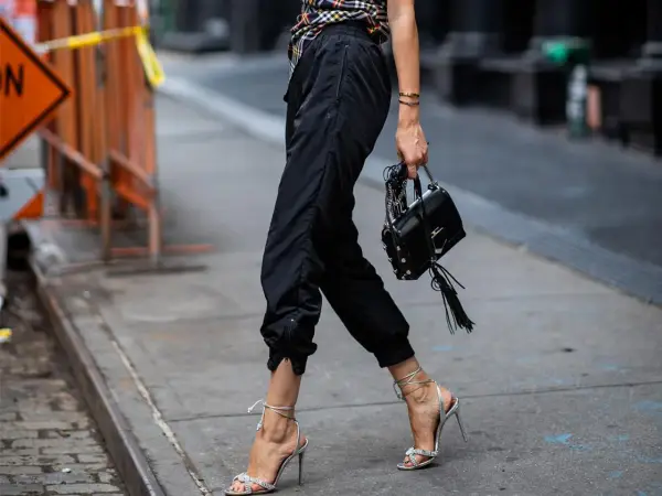 Schwarze Jogginghose kombinieren Herren: lässig mit High Heels und Tasche, ein unerwarteter, aber stylischer Look.